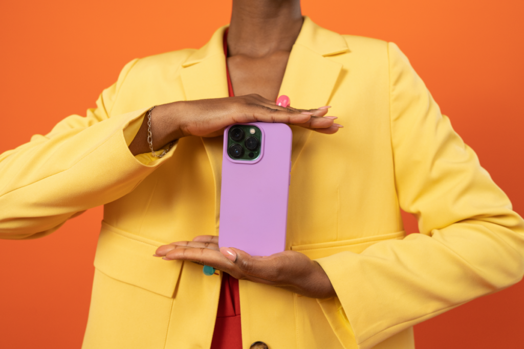 woman in bright yellow jacket holding a cell phone in a pink case.