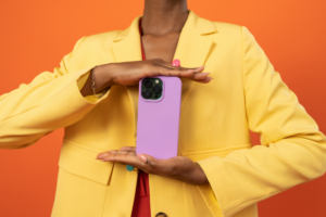woman in bright yellow jacket holding a cell phone in a pink case.
